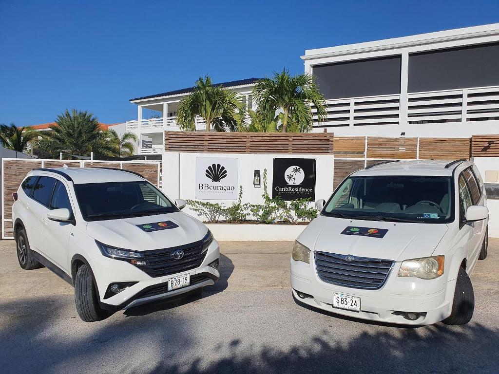 deux voitures blanches garées devant un bâtiment dans l'établissement C APARTMENT at JAN THIEL Curacao, à Jan Thiel