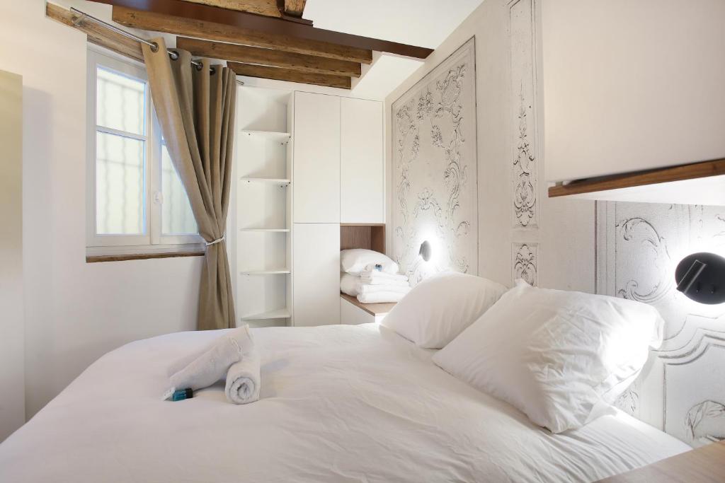 una camera con un letto bianco e una finestra di Apartment Le Marais by Studio prestige a Parigi