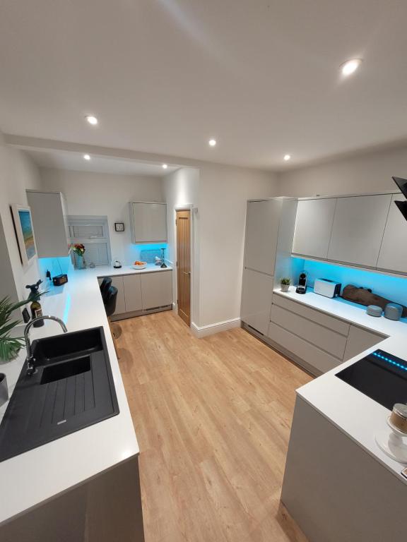 a large kitchen with white cabinets and blue accents at Explore East Devon from here.. in Exmouth