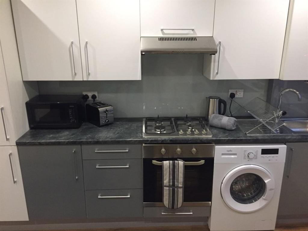 a kitchen with a stove and a washing machine at Showcase Apartments - Kimberley House in Leicester