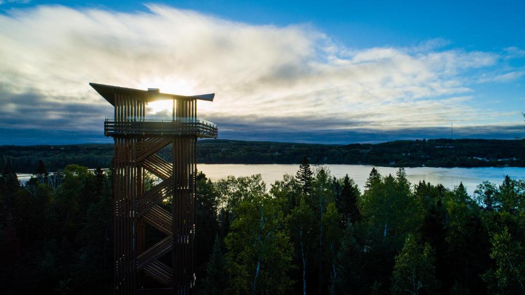 une tour en bois avec le soleil brillant sur elle dans l'établissement Ermitage Saint-Antoine, à Lac-Bouchette