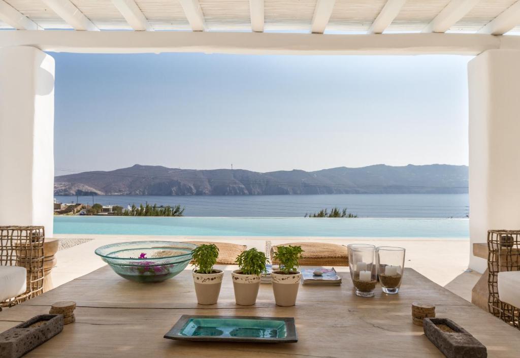 a table with glasses and potted plants on top of a patio at The Margi Villa Mykonos in Agios Sostis Mykonos