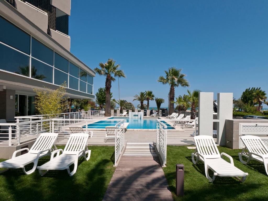 un gruppo di sedie a sdraio bianche accanto alla piscina di Hotel Eden ad Alba Adriatica