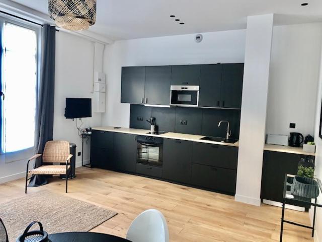 un salon avec une cuisine dotée d'armoires noires dans l'établissement Luxe Parisien - Petit Varenne, à Paris