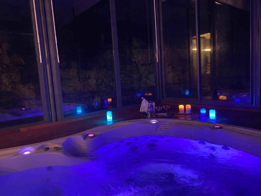 a bath tub with purple lights in a room at Domaine Spa Perret-3Ha-Château ArtDéco MasterSuite B&B ou Gîte de Charme-À3Mn Giverny-Jardins Monet-Le Vexin-Piscine Chauffée en Haute Saison-Aire Enfants-PingPong-Options Dîner-Billard-Massage-Yoga-Coaching-Fitness-Sauna-Hammam-Promo2Nuits Jacuzzi inclus in Sainte-Geneviève-lès-Gasny