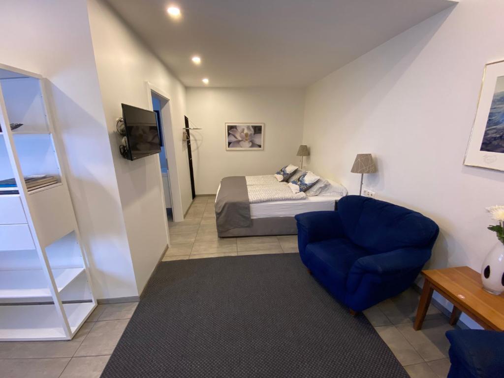een slaapkamer met een bed en een blauwe stoel bij Ace Guesthouse in Keflavík