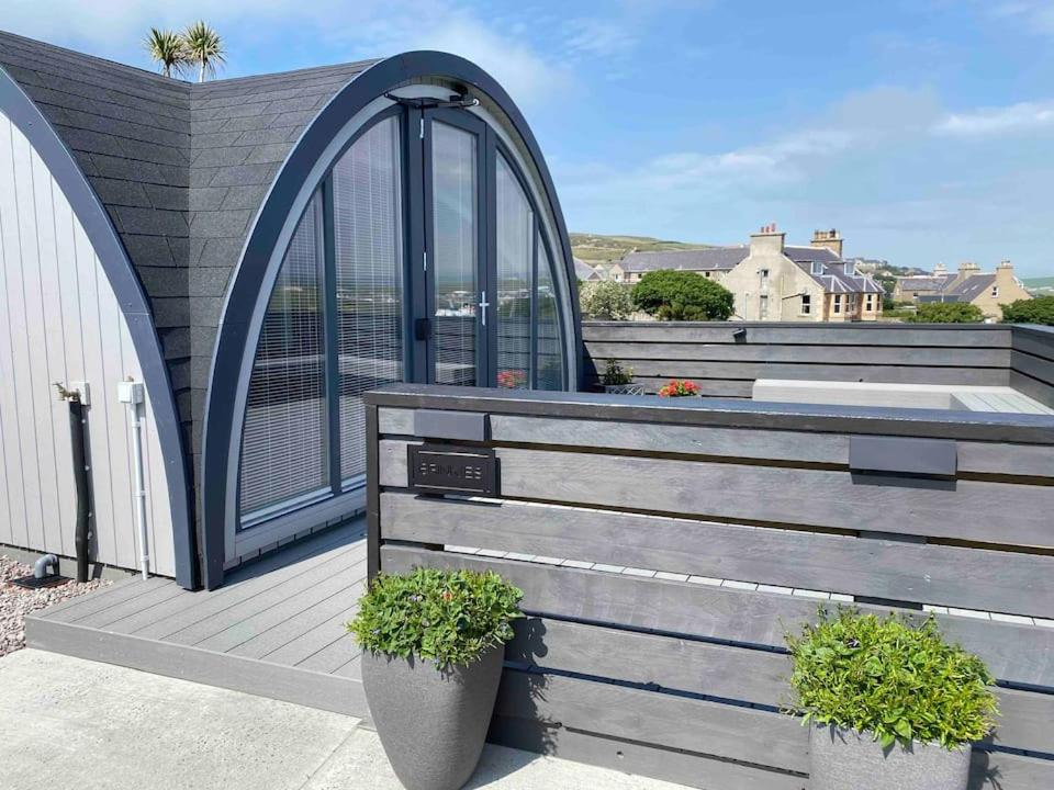 a house with an arbor and a deck with plants at Orkney Lux Lodges - Brinkies Retreat in Stromness