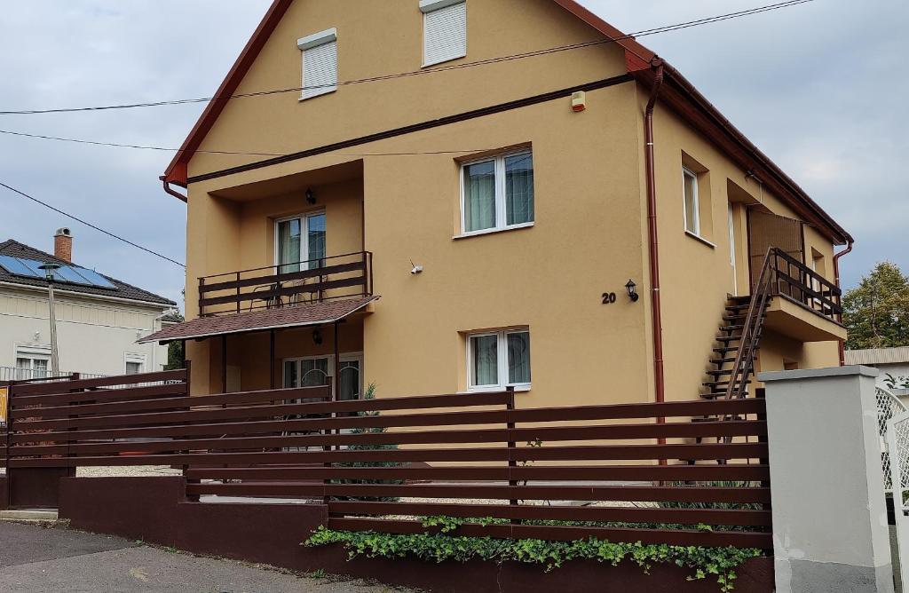 una casa amarilla con una valla delante de ella en Katalin Apartmanház, en Miskolctapolca