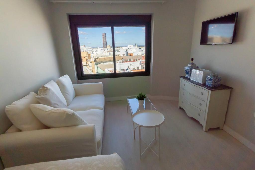 salon z białą kanapą i oknem w obiekcie RentalSevilla Resitur II w Sewilli