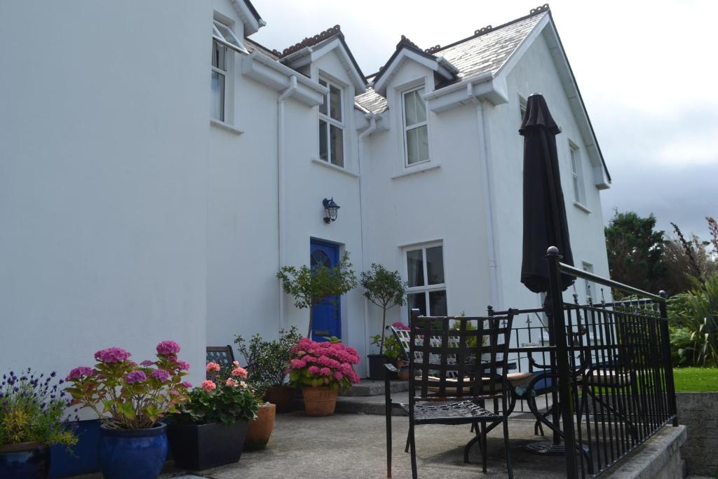 een wit huis met een stoel en een paraplu bij Guaire House Killarney in Killarney