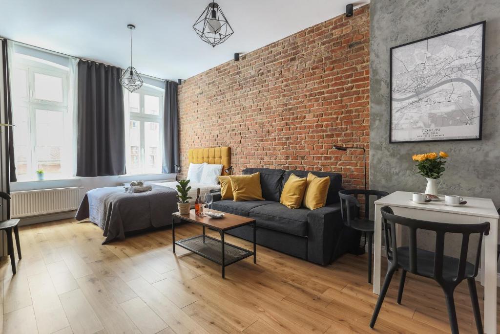 a living room with a couch and a brick wall at Soft Loft 1 Apartment in Toruń