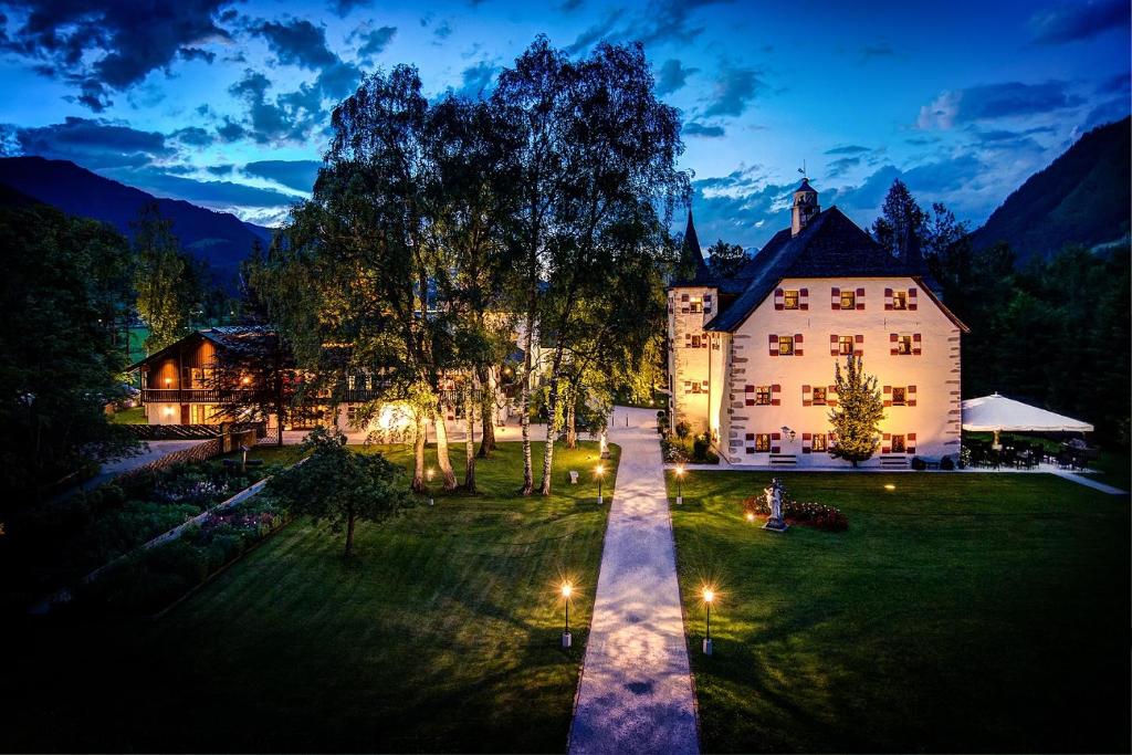 ein großes Haus auf einem Feld mit einem Herrenhaus in der Unterkunft Schloss Prielau Hotel & Restaurants in Zell am See