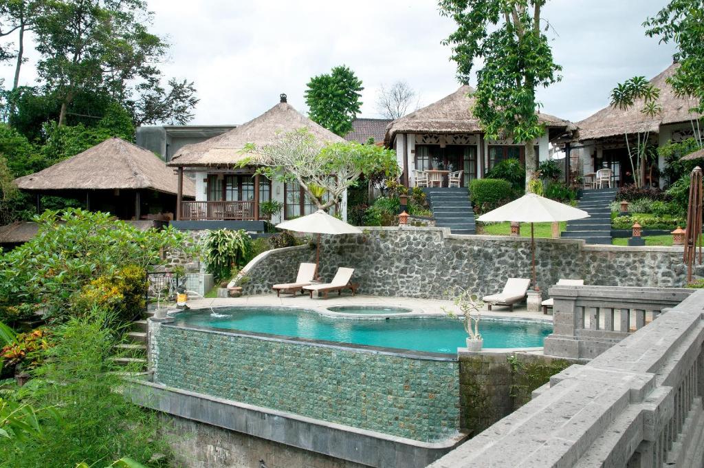 a resort pool with chairs and umbrellas at Ubud Dedari Villas in Ubud