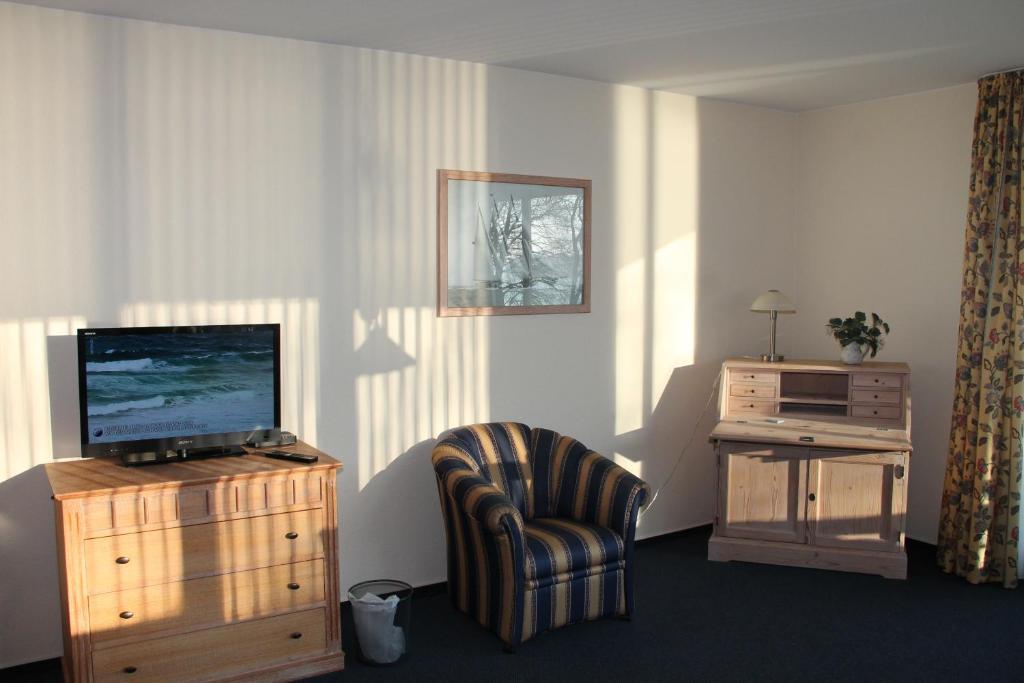 a living room with a tv and a chair at Fewo-Suite mit Seeblick in Ascheberg