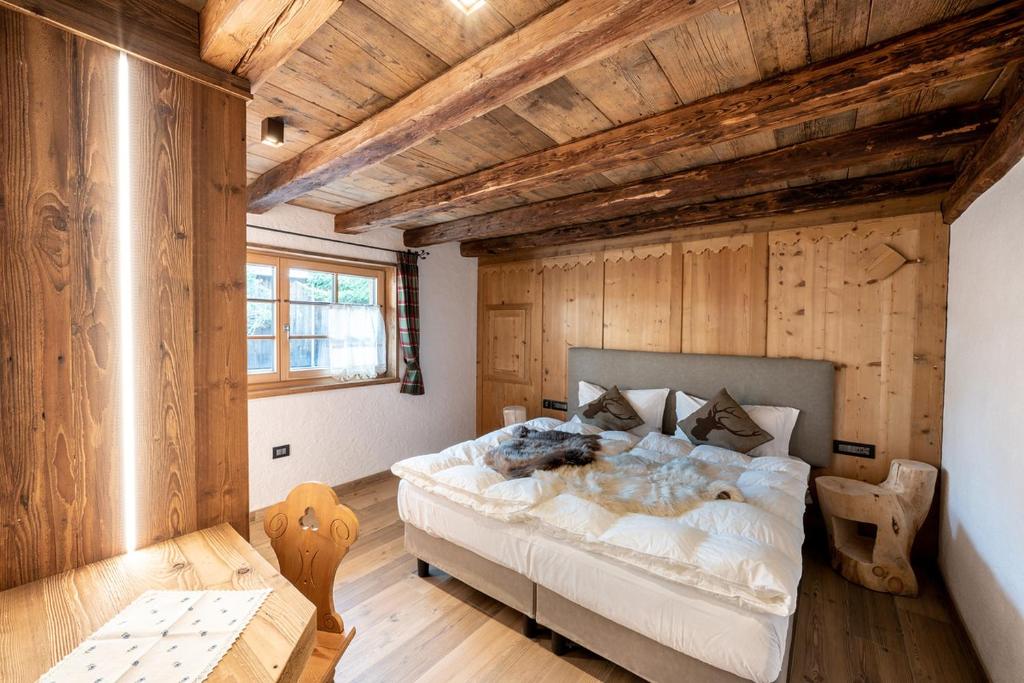 a bedroom with a large bed in a room with wooden walls at Chalet Catinaccio Rosengarten 56 in Pozza di Fassa