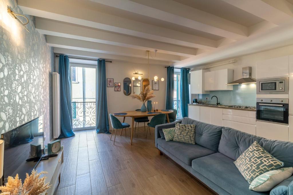 a living room with a blue couch and a kitchen at The Cozy Loft, un angolo alla moda nel cuore di Verona in Verona