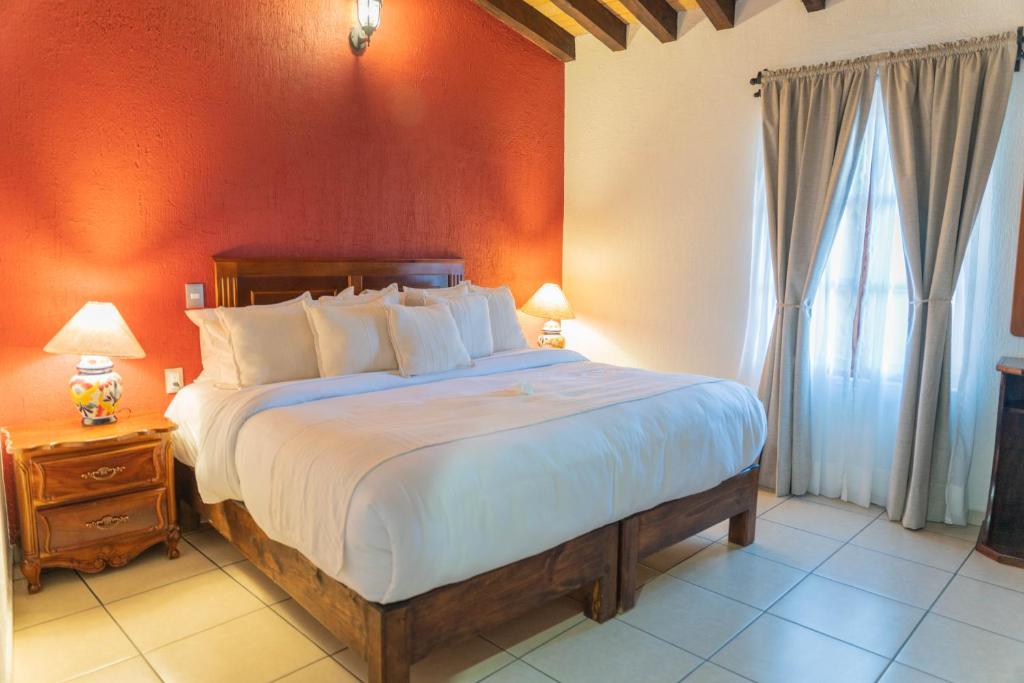 a bedroom with a large bed with an orange wall at Casa Graciela Hotel Pátzcuaro in Pátzcuaro
