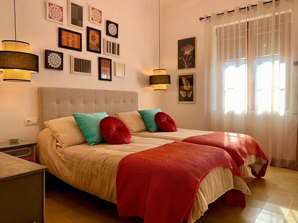 1 dormitorio con 2 camas, almohadas coloridas y ventana en Alojamiento estilo Boho con mucho encanto en Ponferrada