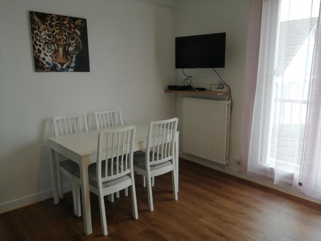 a white dining room table with two chairs and a television at Chaleureux studio tout confort in Orléans