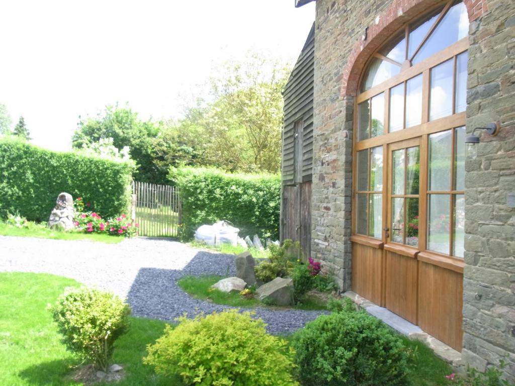 un giardino con una casa in pietra con una porta in legno di Gîte ardennais Rogery - Yá-át-ééh Naşbaş a Gouvy