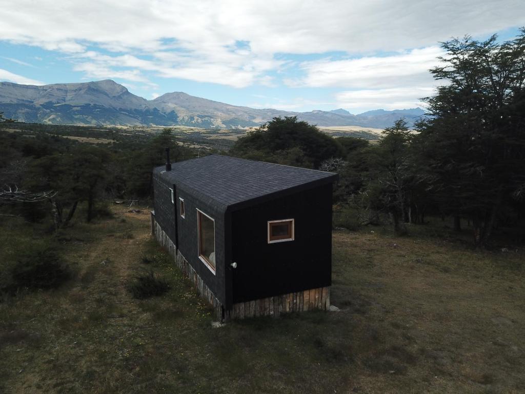 uma pequena casa preta no meio de um campo em Cabaña en Laguna Azul Patagonia Bagual em Torres del Paine