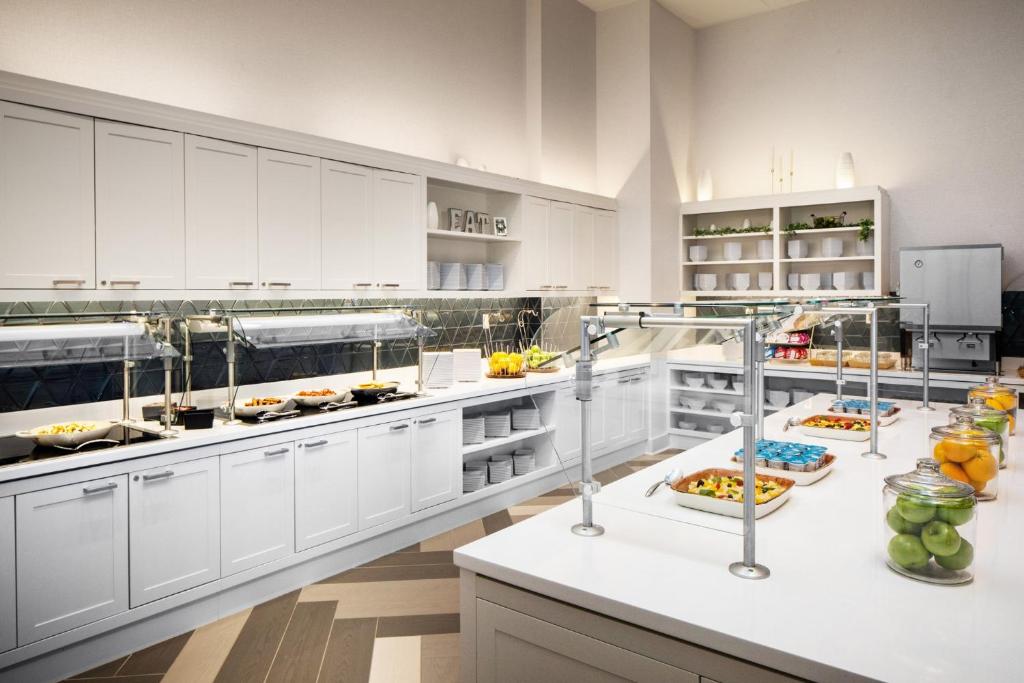 ニューヨークにあるHyatt Place New York Chelseaの白いキャビネットとカウンターの上に食べ物が置かれた広いキッチン