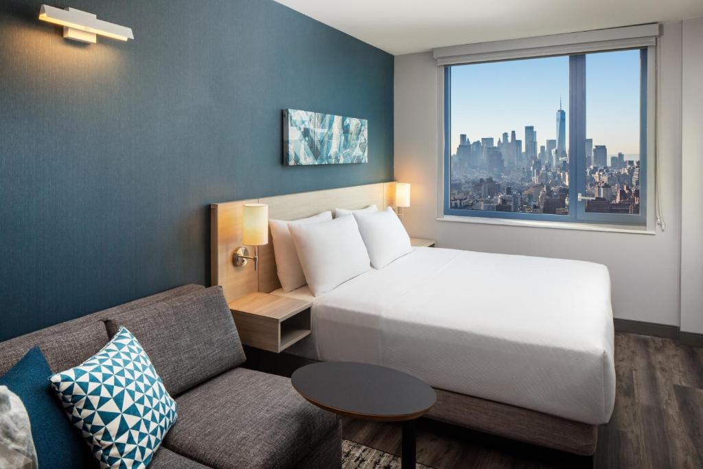 ein Hotelzimmer mit einem Bett, einer Couch und einem Fenster in der Unterkunft Hyatt Place New York Chelsea in New York