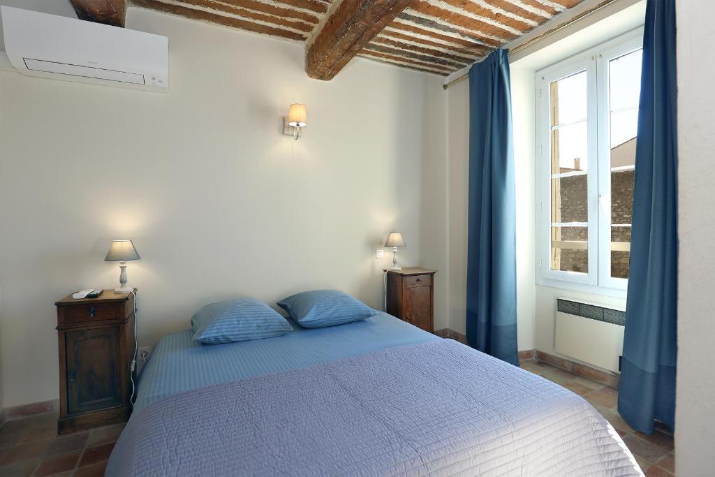 - une chambre avec un lit doté d'oreillers bleus et d'une fenêtre dans l'établissement Le Cheval Blanc, à La Bastide-des-Jourdans