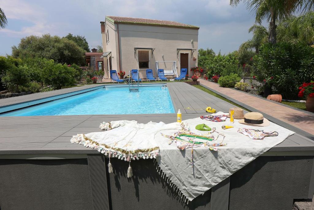 a swimming pool with a table next to a house at Casa delle foglie in San Giovanni la Punta