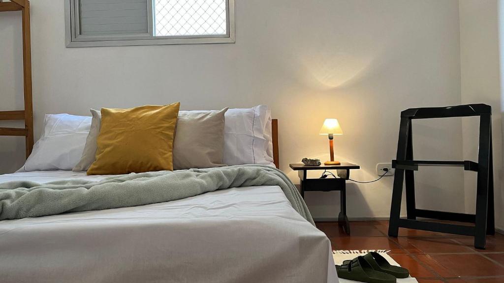 1 dormitorio con 1 cama con almohada amarilla y lámpara en Amplo e confortável em Pitangueiras en Guarujá