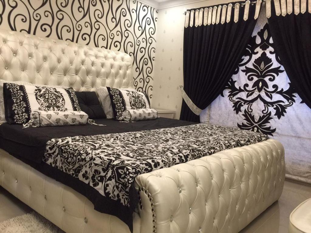 a bedroom with a large white bed with black and white pillows at The Red one bedroom apartment in Bahria Town in Rawalpindi