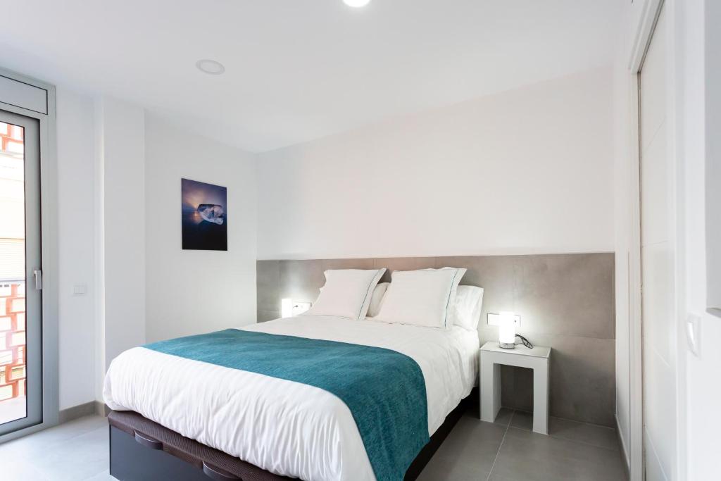 a white bedroom with a large bed and a window at 8 lacus BAIKAL in Hospitalet de Llobregat