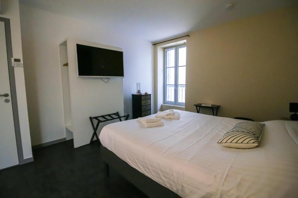 a bedroom with a large white bed with a flat screen tv at Sarlatitude, Studios &amp; Chambres in Sarlat-la-Canéda
