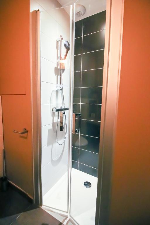 a shower with a glass door in a bathroom at Sarlatitude, Studios &amp; Chambres in Sarlat-la-Canéda
