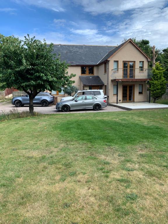 a house with two cars parked in a yard at Tanglewood Lodge in Lossiemouth