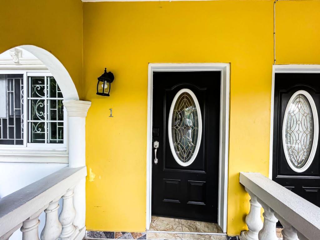 a yellow house with two black doors and windows at Red Hassell Manor in Port Antonio