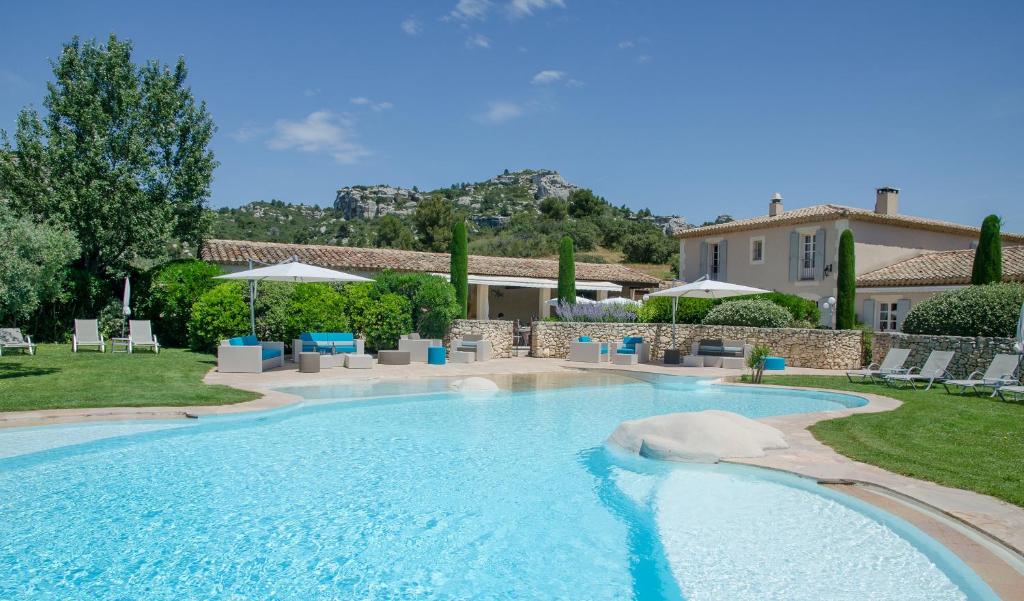 uma piscina num quintal com cadeiras e uma casa em Mas de l'Oulivié em Les Baux-de-Provence