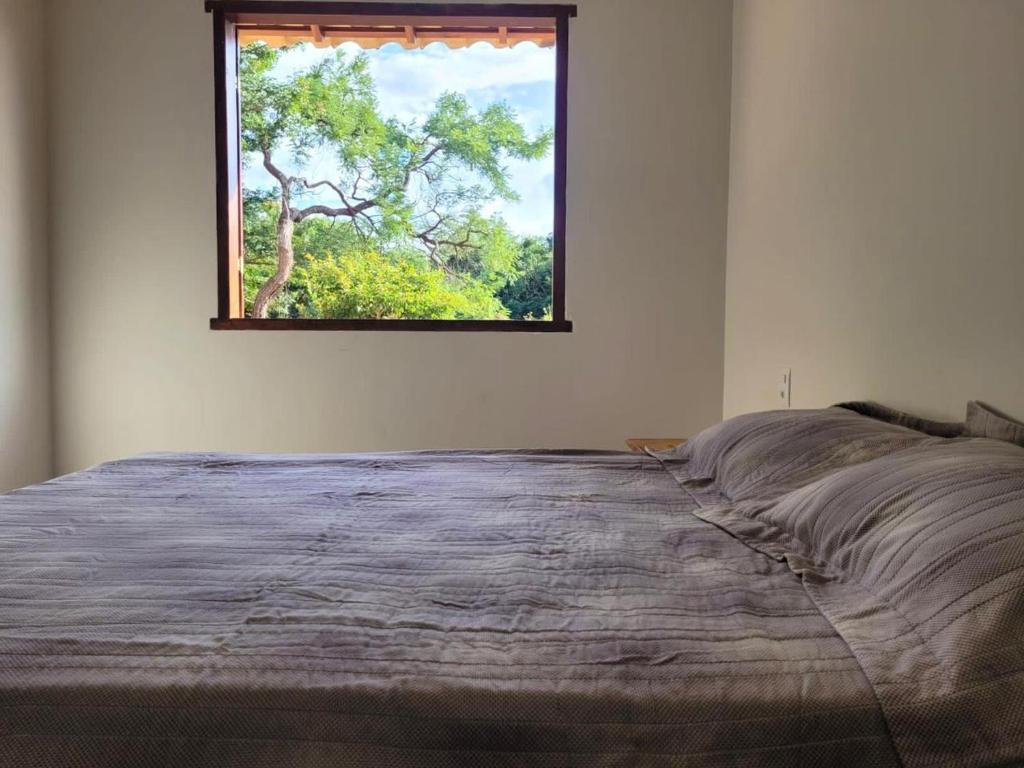 a bedroom with a large bed with a window at Casa Jatobá da Serra in Serra do Cipo