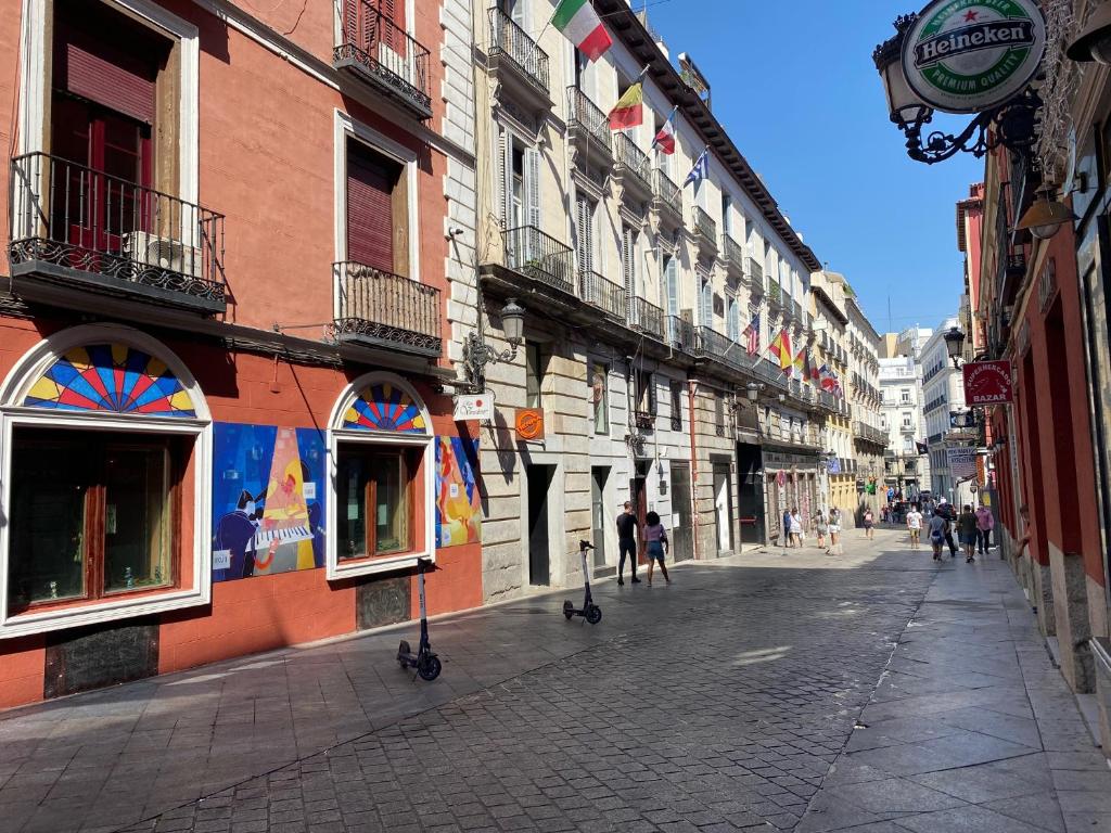 eine Stadtstraße mit Gebäuden und Menschen, die auf der Straße spazieren in der Unterkunft Apartamento Atico en Puerta del Sol in Madrid
