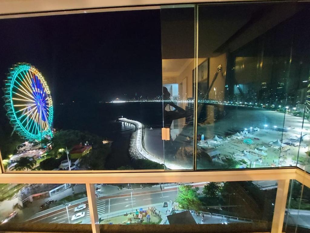 einen Blick auf ein Riesenrad in der Nacht aus einem Fenster in der Unterkunft Apto top, a melhor vista de Balneário Camboriú! in Balneário Camboriú