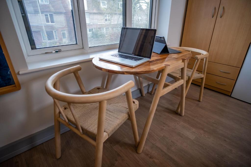 a laptop computer sitting on a wooden table with a chair at Magnolia House, Rye in Rye