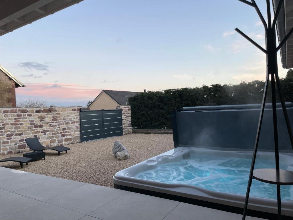 a hot tub on a patio with two chairs at Les chambres d'à côté in Roye