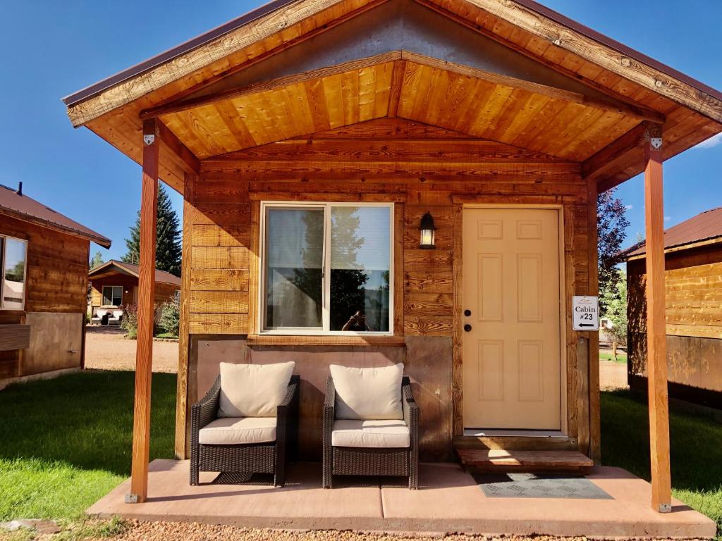 哈奇的住宿－Mountain Ridge Cabins & Lodging Between Bryce and Zion National Park，一个带两把椅子的木制凉亭和白色门
