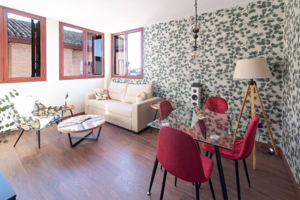 ein Wohnzimmer mit einem Glastisch und roten Stühlen in der Unterkunft Arista Huesca in Huesca