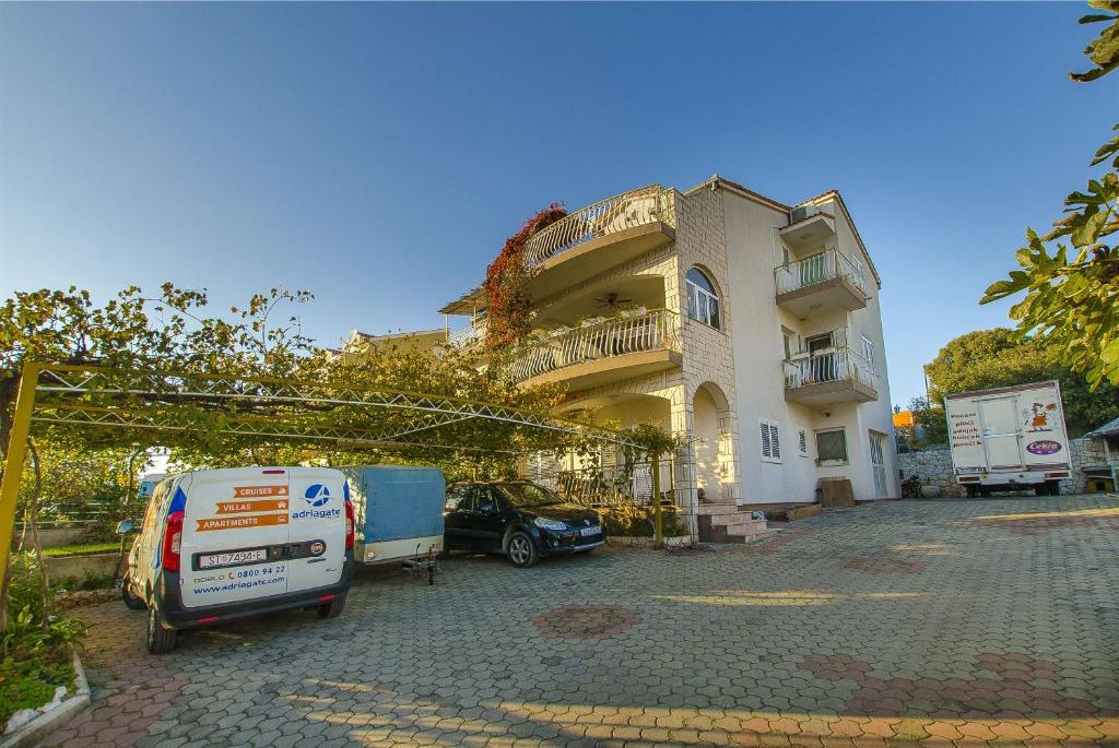 un edificio con dos coches estacionados frente a él en Apartments Nada, en Grebaštica