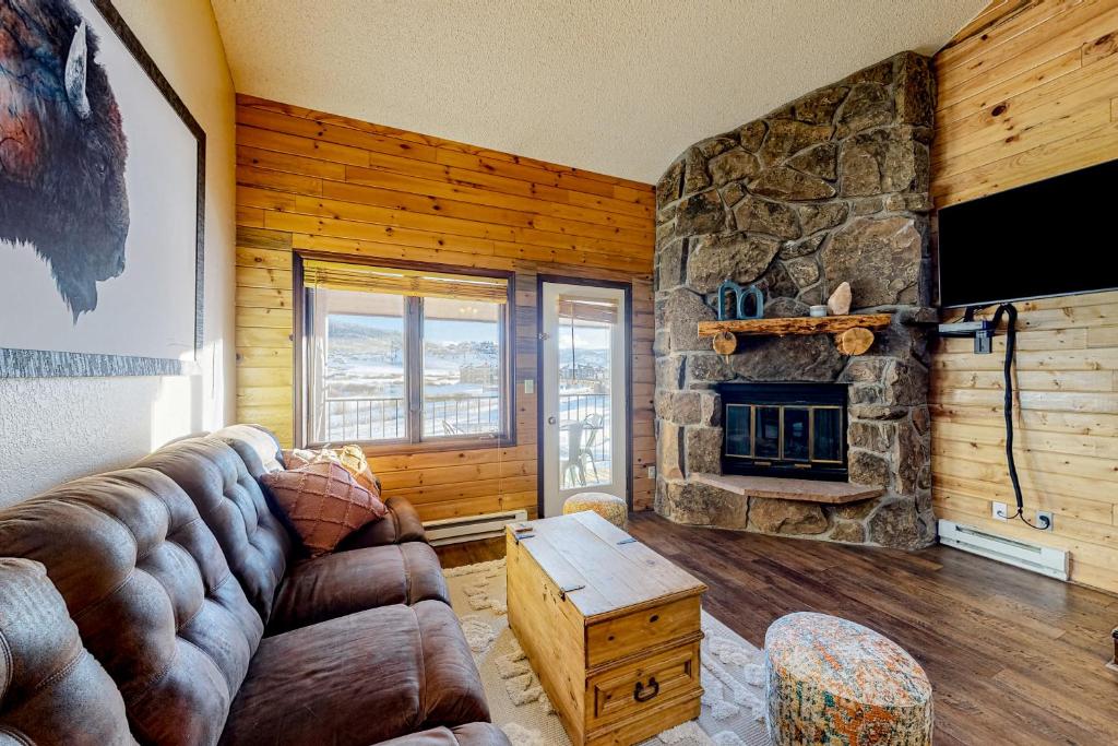 a living room with a couch and a stone fireplace at Buffalo Beauty in Granby