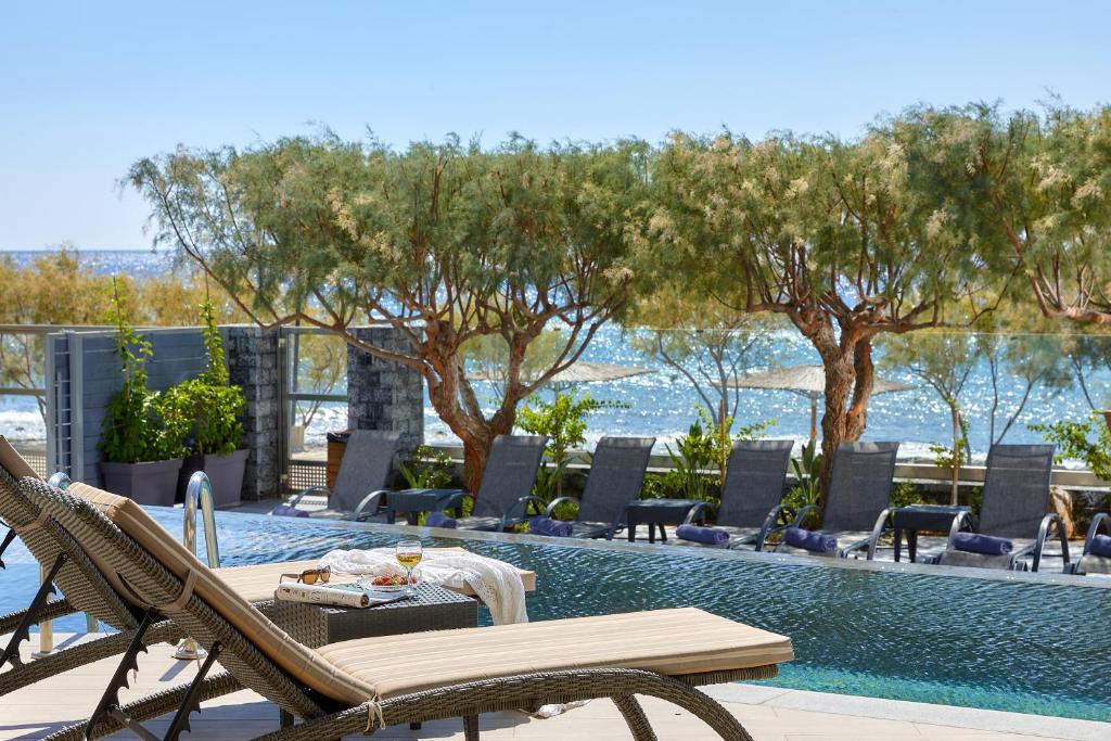 a pool with a table and chairs next to a swimming pool at Moonlight Seafront Apartments in Koutsourás