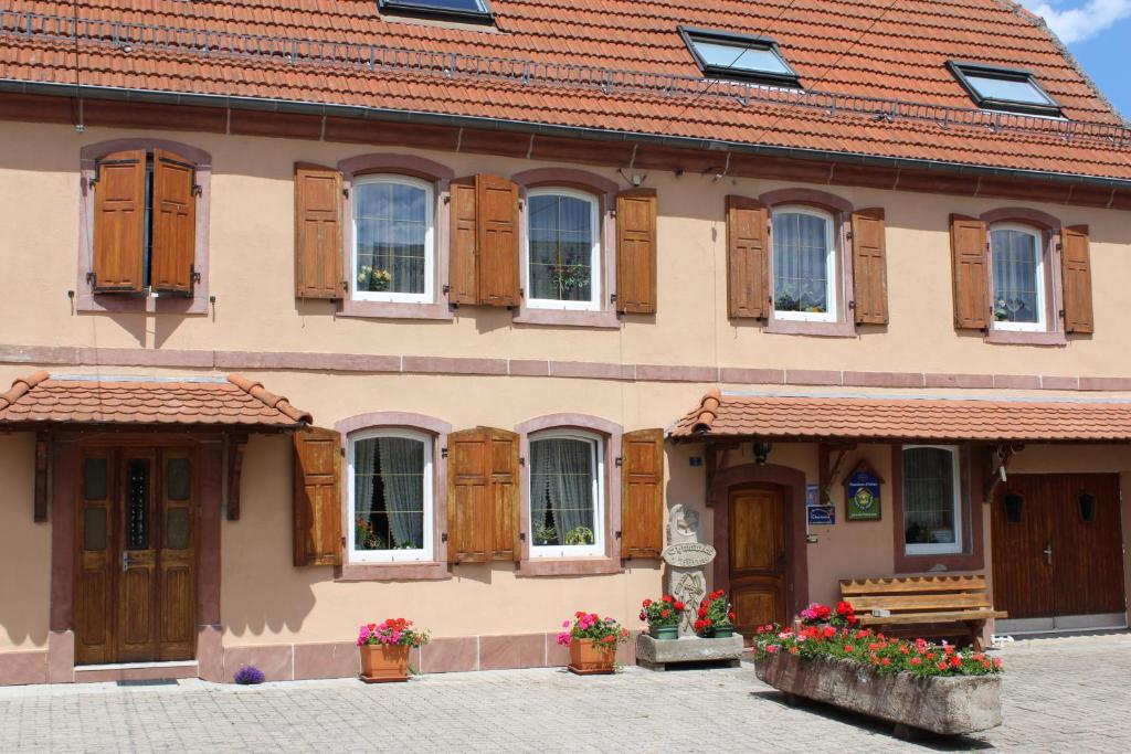 un edificio con puertas y ventanas de madera y flores en CHAMBRES D'HOTES au vieux moulin entre Sarreguemine et Bitche, en Rahling