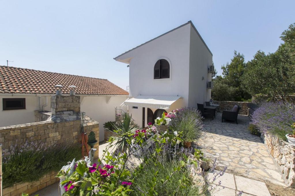 a garden with a white house and some flowers at Apartments Danica in Murter