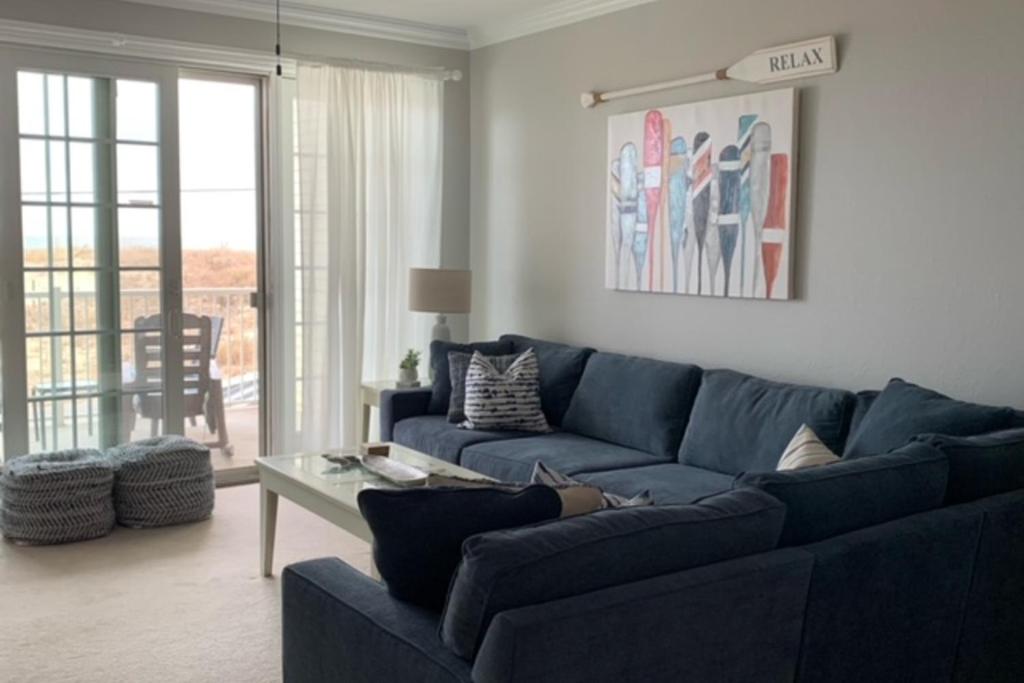 a living room with a blue couch and a table at The Sandbridge Dunes - Salty Mermaid 110 in Virginia Beach